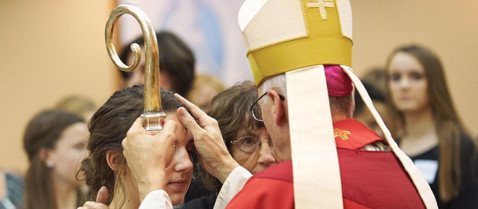 Un obispo impone las manos sobre una joven invocando al Espíritu Santo
