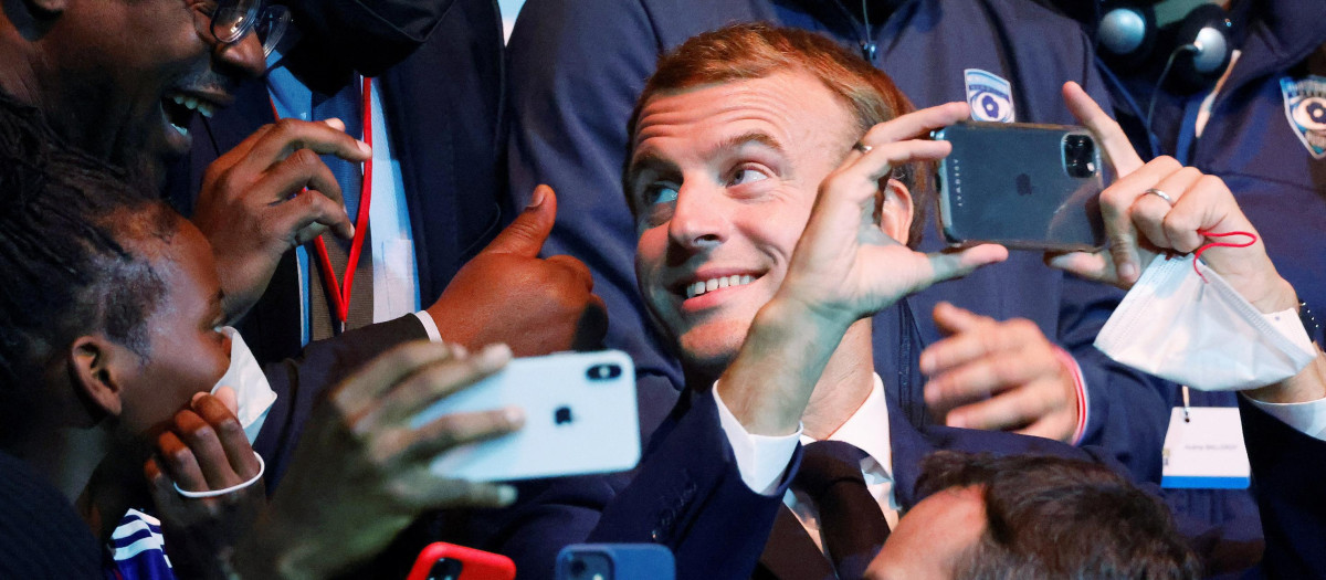 Emmanuel Macron (C) se toma una selfie mientras asiste a un juego de baloncesto