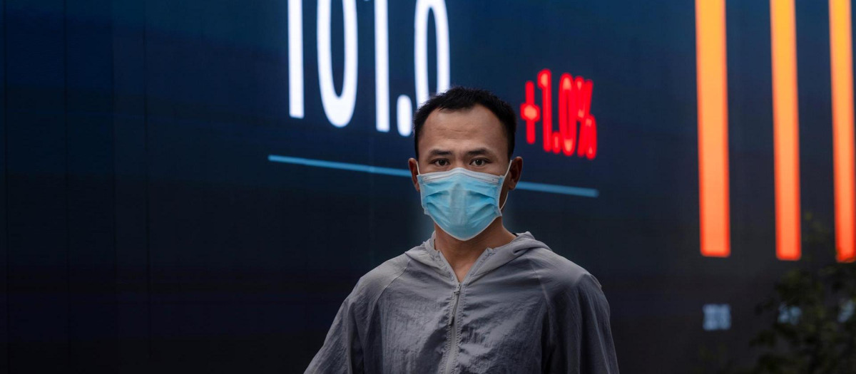 Un hombre camina frente a las pantallas de la bolsa de Shanghai, China