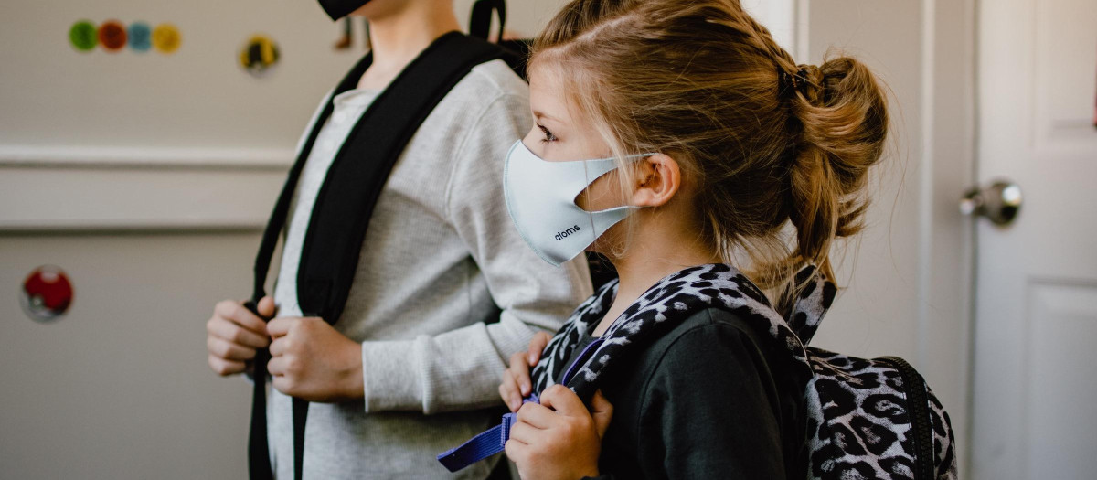 Dos niños con con mascarilla preparados con las mochilas de la escuela
