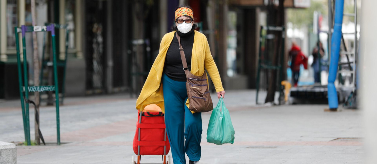 Una mujer camina después de hacer la compra (Madrid)