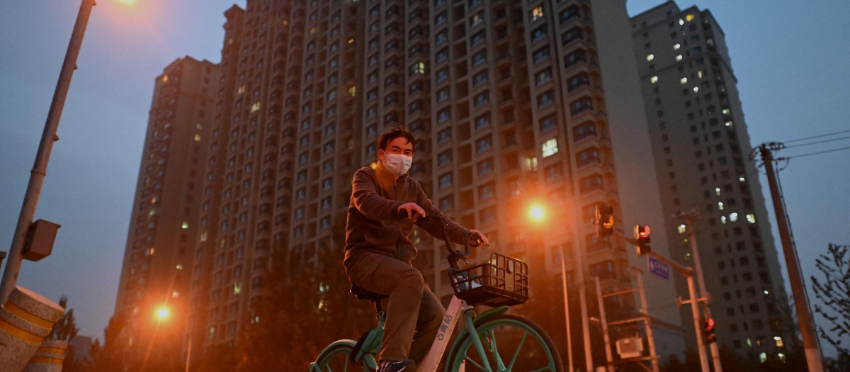 Un hombre monta en bicicleta frente a un complejo de viviendas de Evergrande en China