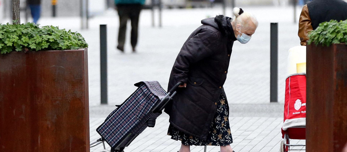 Una anciana camina por la calle en dirección al supermercado