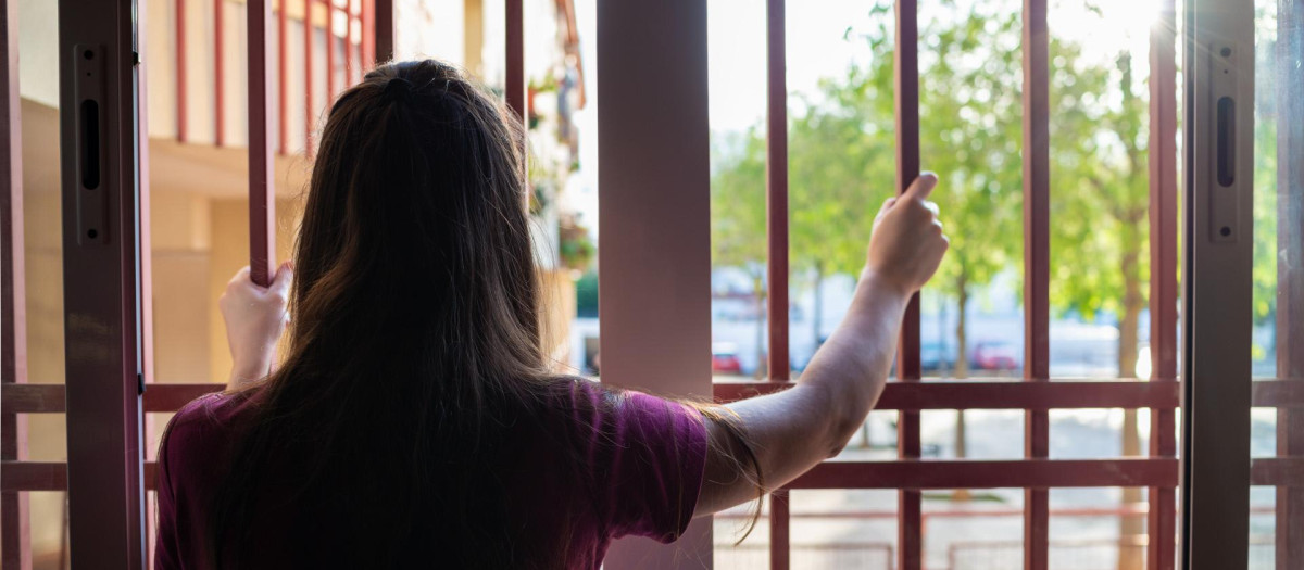 Chica mirando por la ventana durante la cuarentena