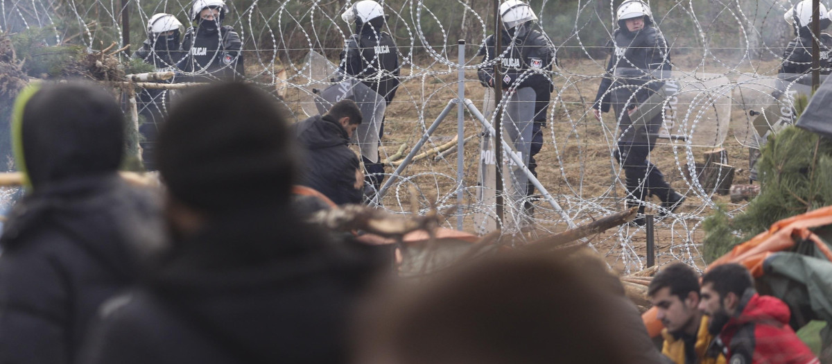 Soldados polacos observan desde su lado de la frontera a los refugiados y migrantes