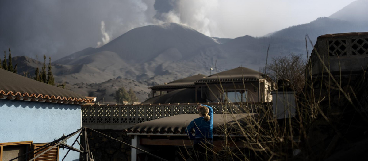 Una mujer observa el volcán de Cumbre Vieja antes de abandonar su vivienda