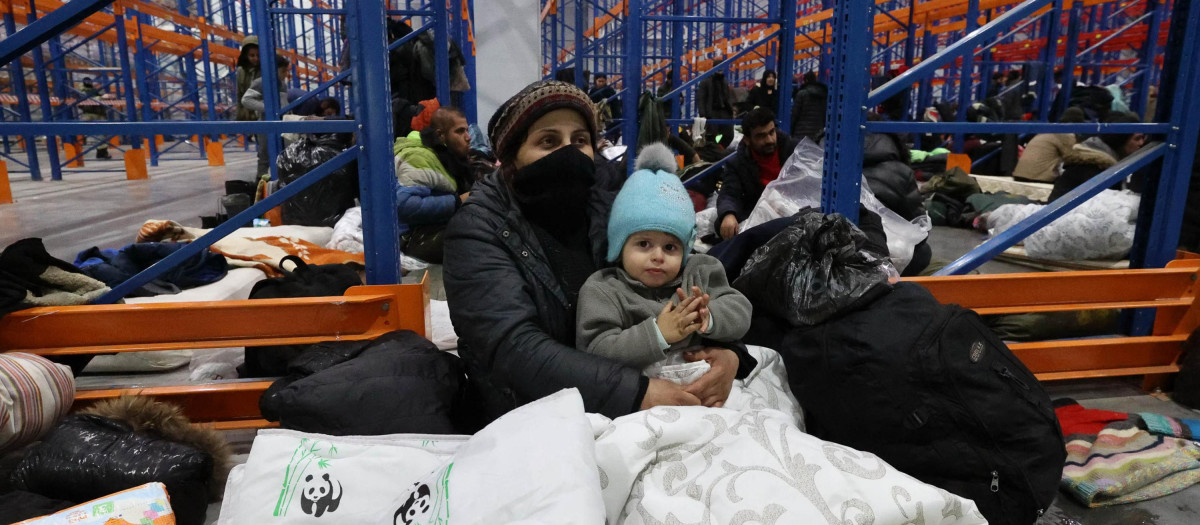 Migrantes refugiándose del frio en una caja de transportes en la frontera con Bielorrusia