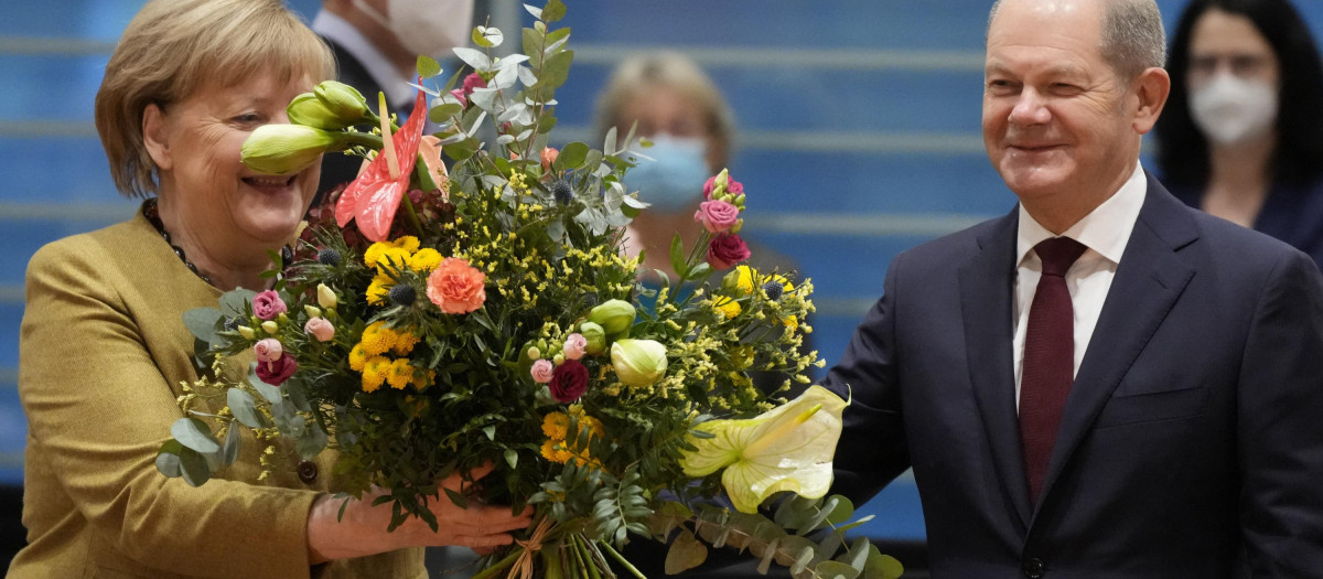 El nuevo canciller Olaf Scholz entrega un ramo de flores a Angela Merkel en su última reunión con el gabinete