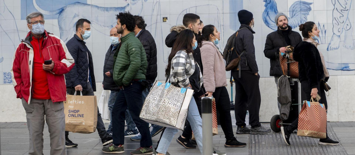 Varias personas caminan con bolsas con compras