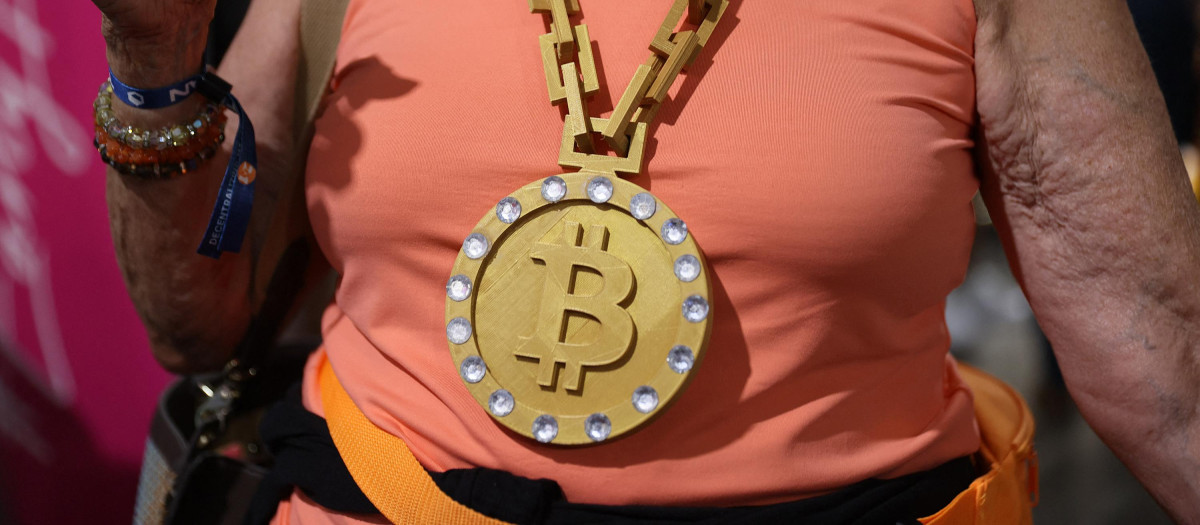 Una mujer lleva una medalla con el símbolo del bitcoin en una convención de criptomonedas