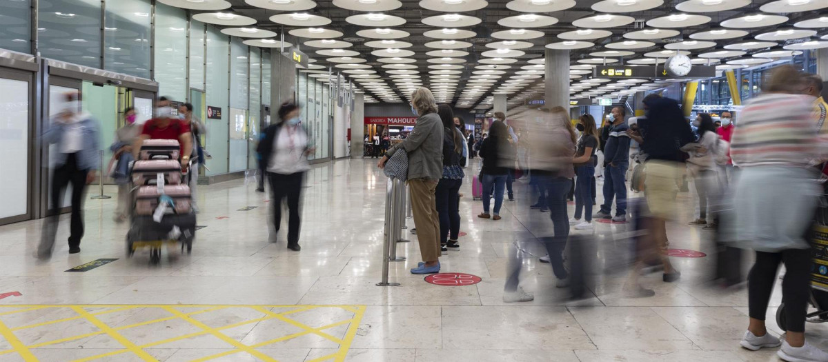 Un hombre espera mientras otros pasajeros llegan a la Terminal T4 del Aeropuerto Adolfo Suárez Madrid - Barajas