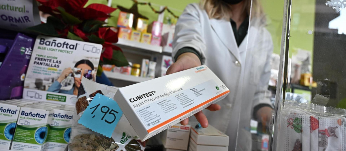 Una farmaceútica muestra el último test de antígenos que tiene disponible a la venta en su farmacia de Madrid