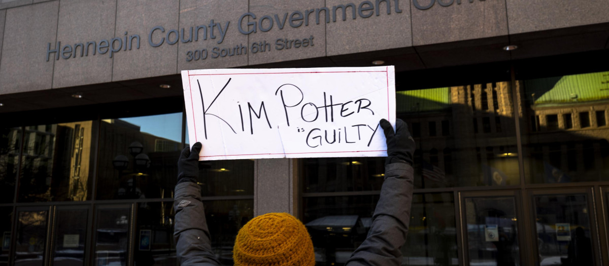 Una mujer sostiene un cartel que dice "Kim Potter culpable" frente al juzgado donde se ha declarado culpable a la policía de homicidio involuntario