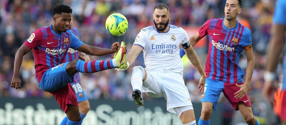 El delantero francés del Real Madrid Karim Benzema disputa el balón con los jugadores del FC Barcelona Ansu Fati y Sergio Busquets