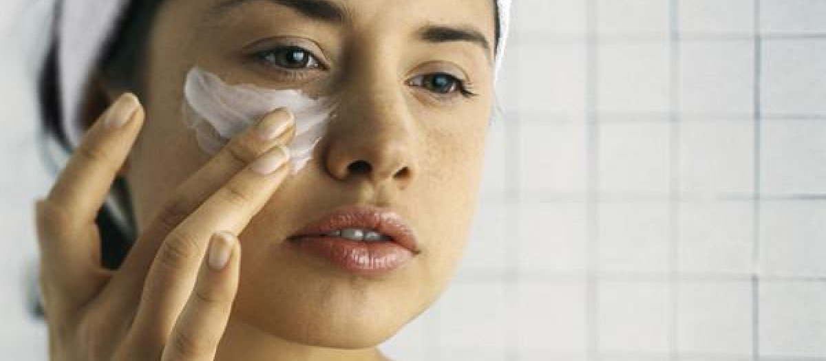 Young woman moisturizing face, close-up 
mujer jóven hidratación cuidado estético cuidado de la piel crema para el contorno de ojos crema cremas una persona 20-24 años solo jóvenes adultos sólo adultos solo mujeres sólo mujeres jóvenes mujer una mujer jóven sola joven adulto adulto rutina prevención belleza protección anti-edad cuidadoso de su cuerpo coquetería crema anti arrugas loción vincha día interior mañana aplicar tez piel hermosa mejilla guapa hidratante mirar para otro lado hidratar cabeza y hombros vista parcial imágen a color primer plano bretel pared embaldosada vista acotada cropeo adultos mujeres mejillas hermosas guapas hidratantes linda bonita lociones rutinario atento a su cuerpo vistas parciales vistas acotadas cropeos tirantes vistas parsiales photoalto