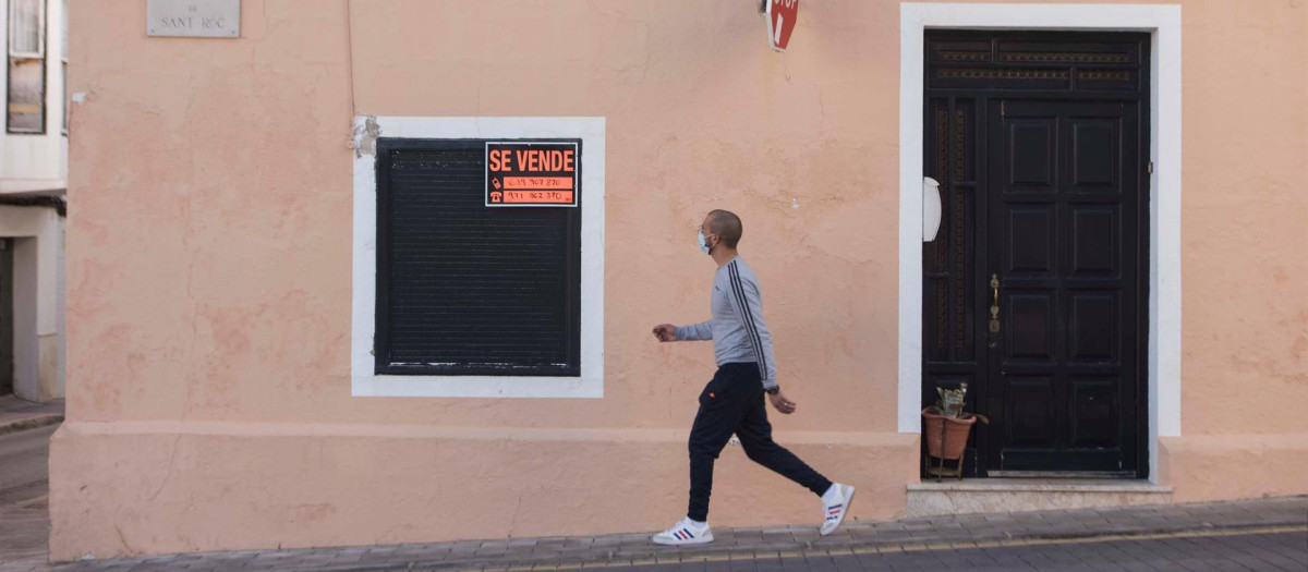 Un transeúnte camina delante de una vivienda en venta