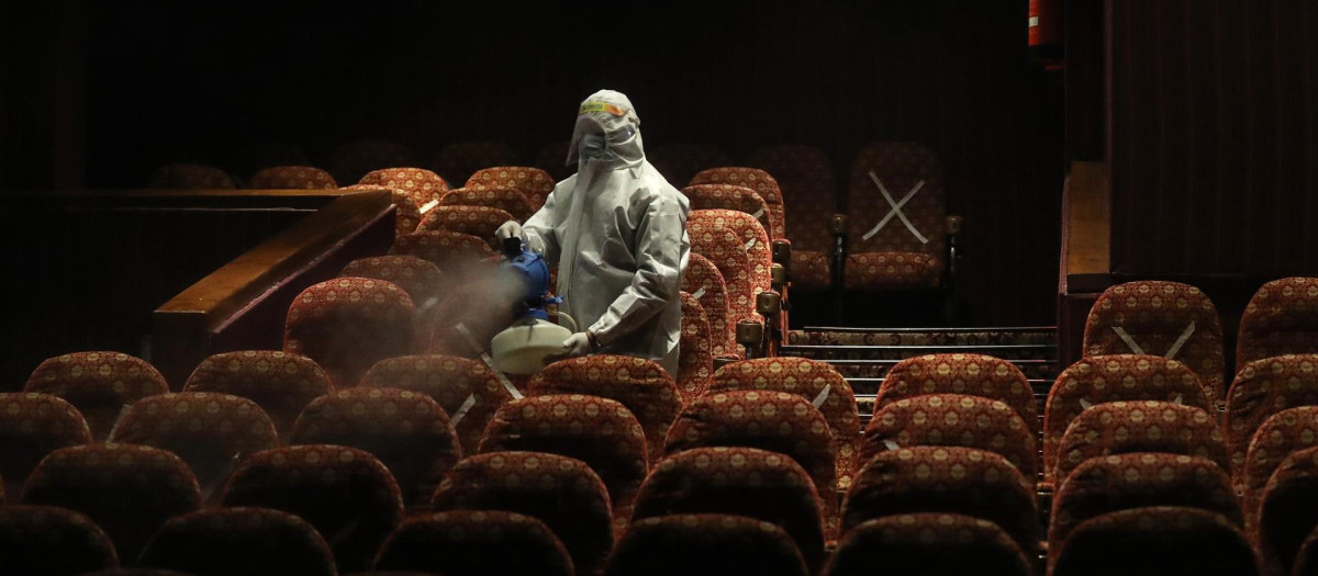 Un empleado sanitario desinfecta los asientos de una sala de cine en Nueva Delhi