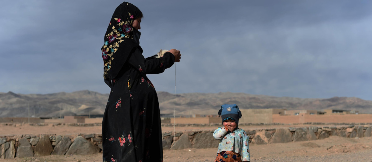 Una mujer afgana hila lana mientras está de pie cerca de su casa en la zona de Sayshanba Bazar en el distrito de Injil de la provincia de Herat