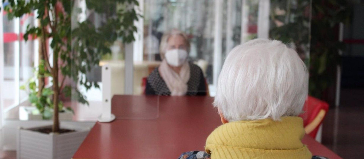 Dos mujeres charlan a través de un cristal en una residencia de Castilla-La Mancha