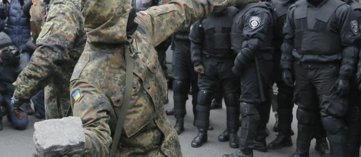 Un miliaciano ucranio lanza una piedra contra la fachada del Sberbank en Kiev