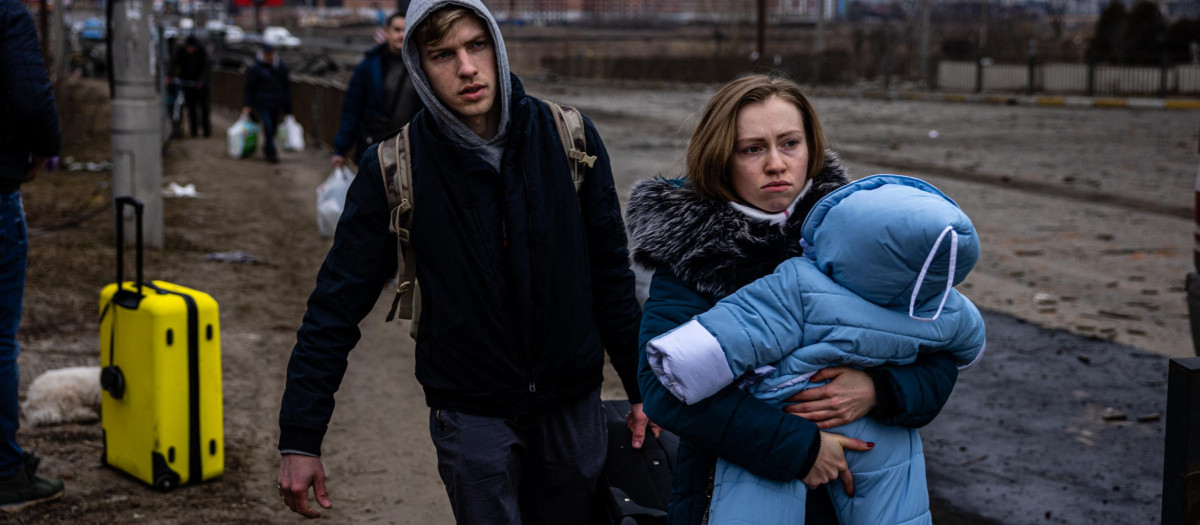 Una mujer carga a su hijo mientras huyen de la ciudad de Irpin, al noroeste de Kiev