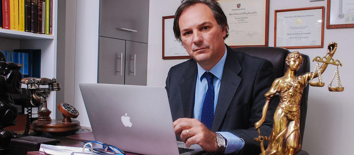 Un abogado trabajando en su despacho frente a una imagen de la Justicia