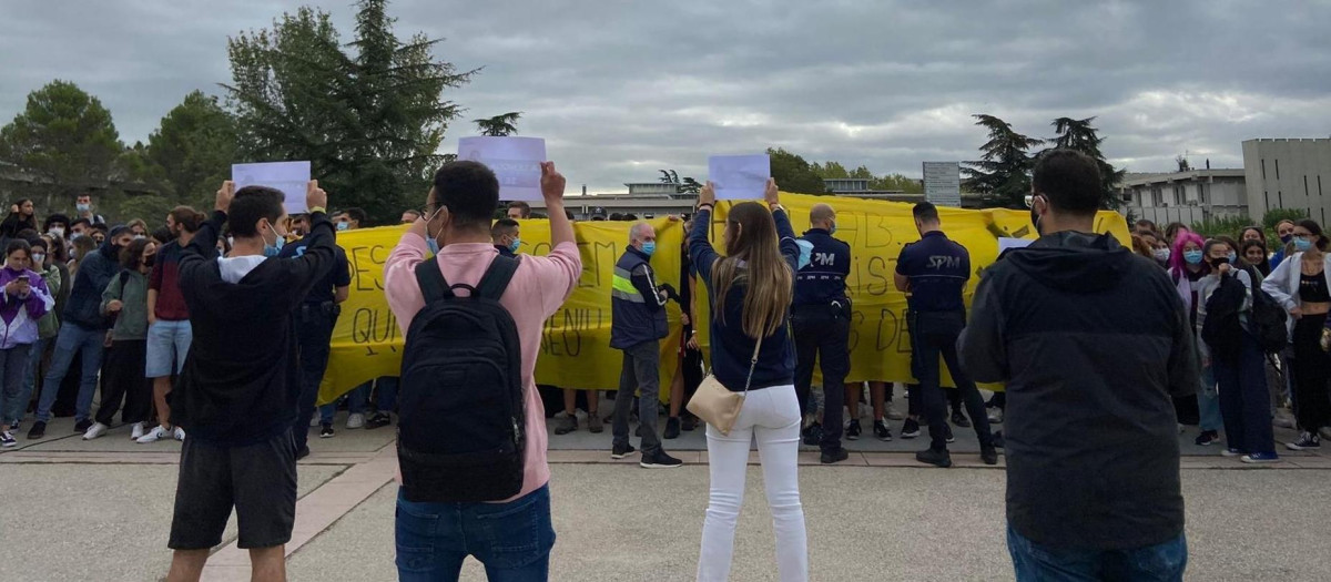 Miembros de la organización estudiantil 'S'ha acabat!' exhiben carteles frente a una concentración ante su carpa informativa en el campus de la UAB