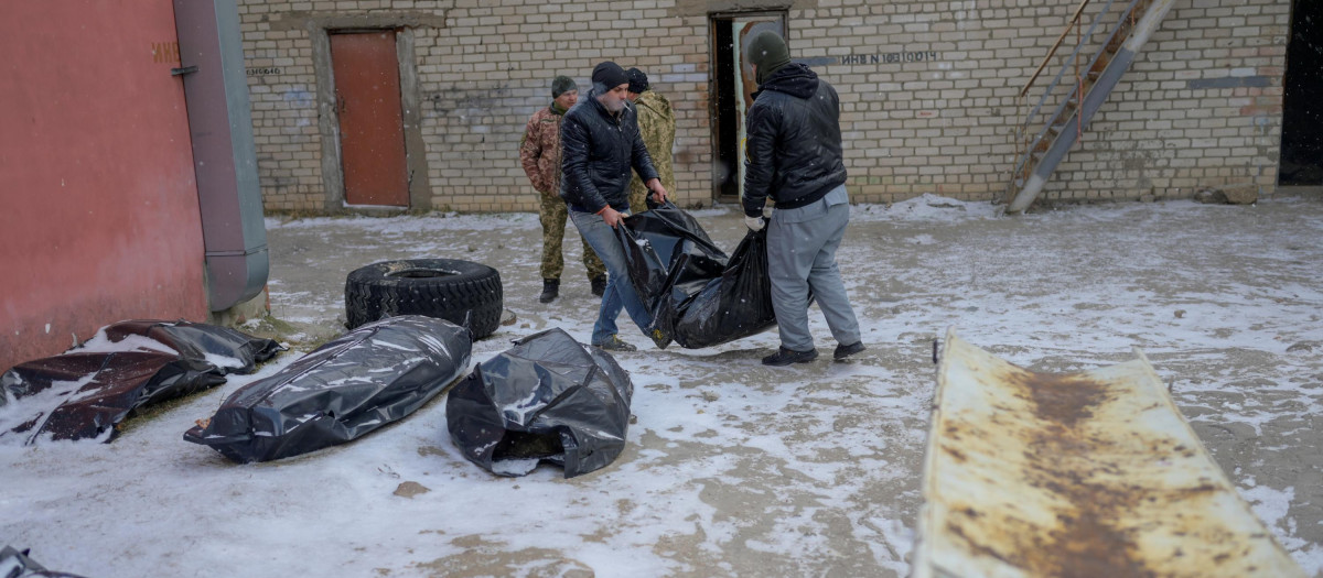 Dos hombres ucranianos cargan con el cuerpo de un fallecido tras una ataque ruso.