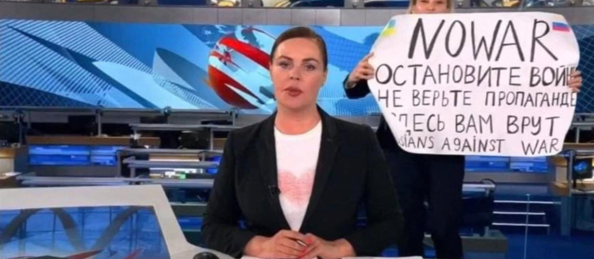 This video grab taken on March 15, 2022 shows Russian Channel One editor Marina Ovsyannikova holds a poster reading " Stop the war. Don't believe the propaganda. Here they are lying to you"  during on-air TV studio by news anchor Yekaterina Andreyeva , Russia's most-watched evening news broadcast, in Moscow on March 14, 2022 . - As a news anchor Yekaterina Andreyeva launched into an item about relations with Belarus, Marina Ovsyannikova, who wore a dark formal suit, burst into view, holding up a hand-written poster saying "No War" in English. (Photo by Handout / AFP) / RESTRICTED TO EDITORIAL USE - MANDATORY CREDIT "AFP PHOTO / Channnel One  - NO MARKETING NO ADVERTISING CAMPAIGNS - DISTRIBUTED AS A SERVICE TO CLIENTS