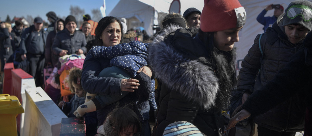 People wait for transportation after crossing the Ukrainian border into Poland, in Medyka, eastern Poland, on March 11, 2022. - Some 2.5 million people have fled Ukraine since Russia invaded two weeks ago, and another two million have been internally displaced by the war, the United Nations said on March 11, 2022. (Photo by Louisa GOULIAMAKI / AFP)