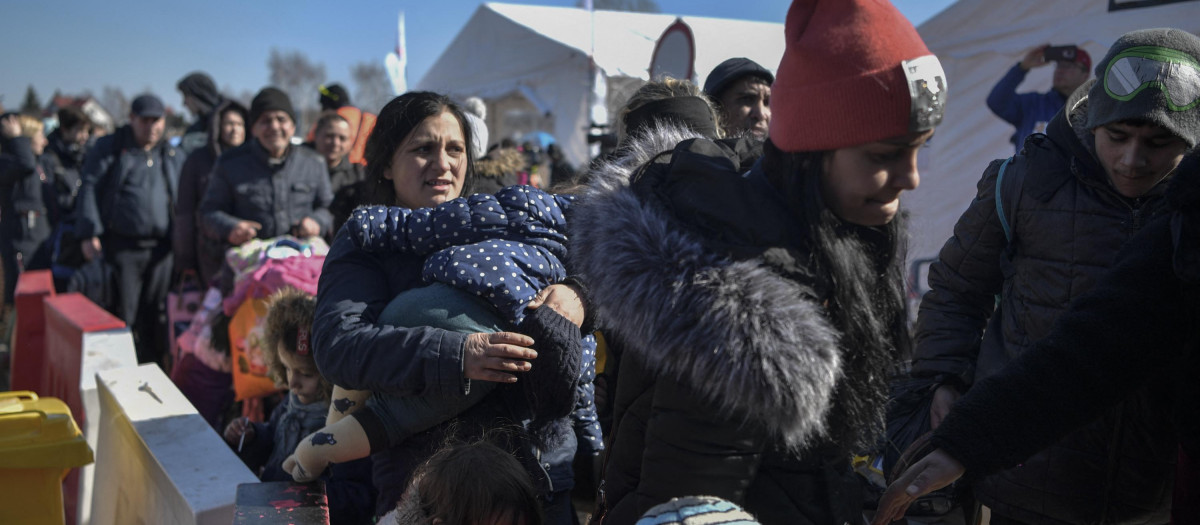 People wait for transportation after crossing the Ukrainian border into Poland, in Medyka, eastern Poland, on March 11, 2022. - Some 2.5 million people have fled Ukraine since Russia invaded two weeks ago, and another two million have been internally displaced by the war, the United Nations said on March 11, 2022. (Photo by Louisa GOULIAMAKI / AFP)