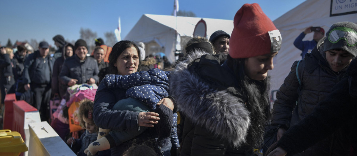 People wait for transportation after crossing the Ukrainian border into Poland, in Medyka, eastern Poland, on March 11, 2022. - Some 2.5 million people have fled Ukraine since Russia invaded two weeks ago, and another two million have been internally displaced by the war, the United Nations said on March 11, 2022. (Photo by Louisa GOULIAMAKI / AFP)