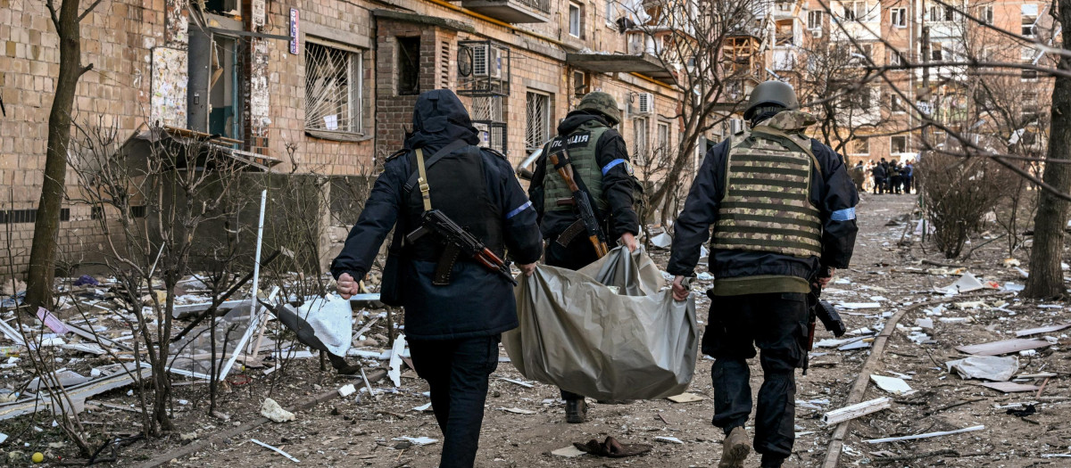 Policías ucranianos transportan un cadáver tras un bombardeo a un edificio residencial