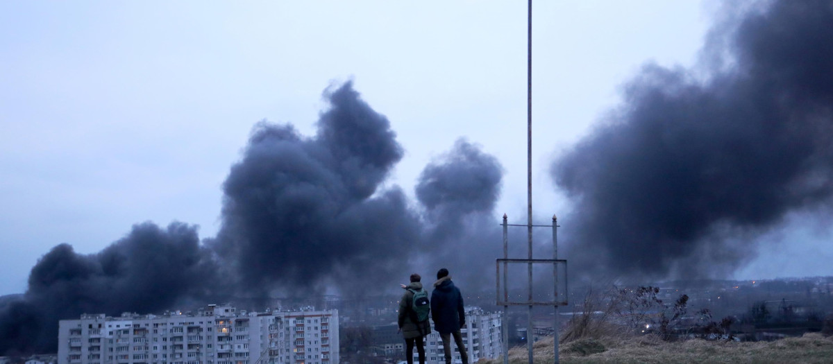 Dos personas observan las llamas que se elevan de un incendio tras el ataque aéreo contra la ciudad de Léopolis, Ucrania