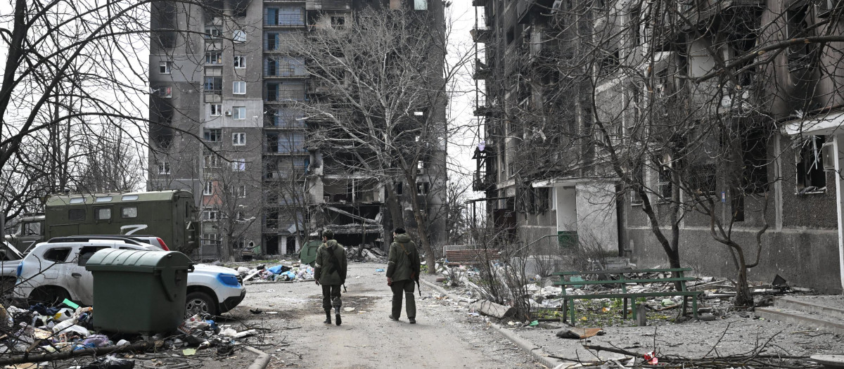 Dos soldados caminan entre edificios destruidos por los ataques rusos en Mariúpol