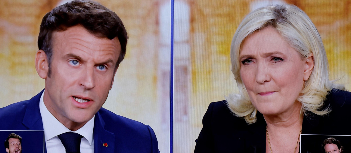 A picture shows screens displaying a live televised debate between French President and La Republique en Marche (LREM) party candidate for re-election Emmanuel Macron (L) and French far-right party Rassemblement National (RN) presidential candidate Marine Le Pen (R), broadcasted on French TV channels TF1 and France 2, in a viewing roon at the studios hosting the debate in Saint-Denis, north of Paris, ahead of the second round of France's presidential election. - French voters head to the polls for a run-off vote between Macron and Le Pen on April 24, 2022. (Photo by Ludovic MARIN / AFP)