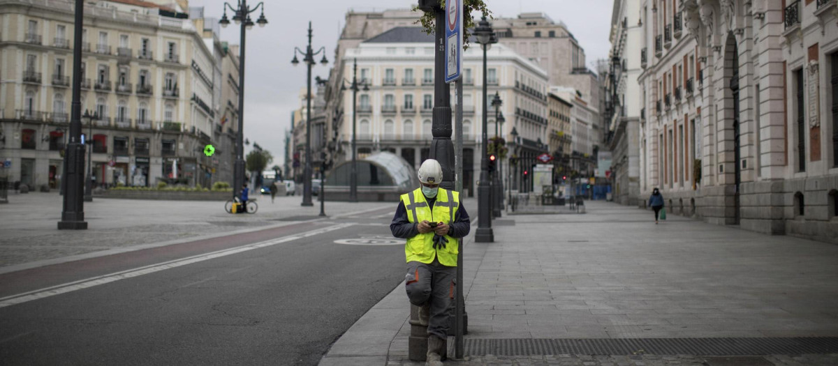 Un trabajador consulta el móvil en pleno confinamiento en Madrid