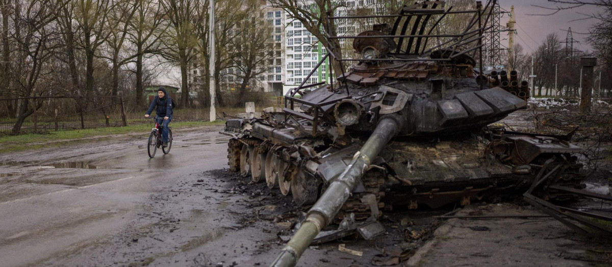 Un hombre monta en bicicleta junto a un tanque destruido en la ciudad ucraniana de Chernígov, el 21 de abril