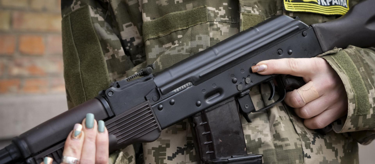 Una mujer sostiene un rifle de asalto Kalashnikov por las calles de Kiev, Ucrania