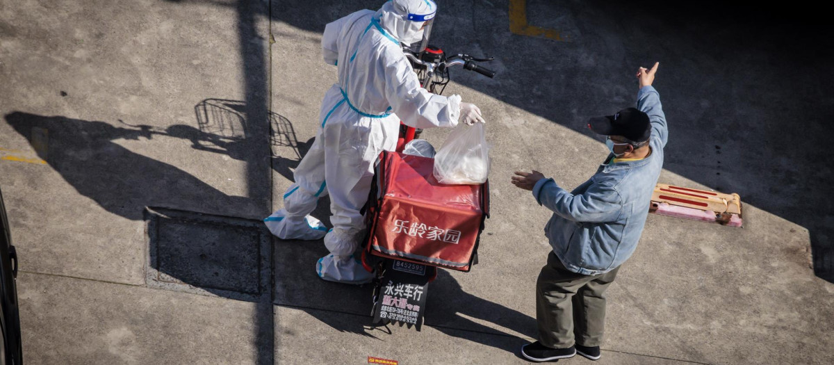 Un hombre en cuarentena recibe su pedido en medio del confinamiento por la COVID-19 en Shanghái, China