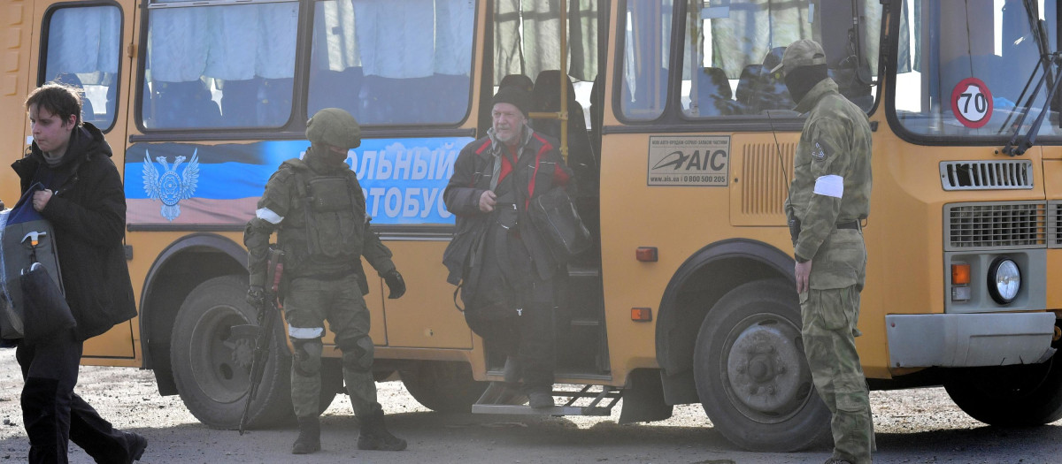Un civil baja de un autobús escoltado por militares después de ser evacuado de la zona de Azovstal, en Mariúpol, asediada por las tropas rusas