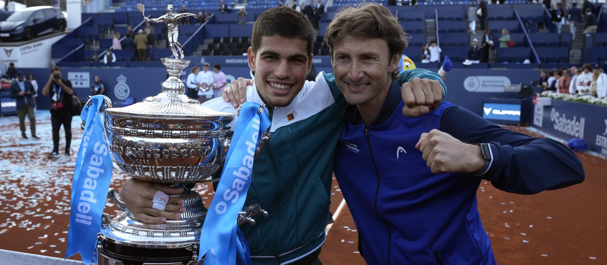 BARCELONA, 24/04/2022.- El tenista español Carlos Alcaraz (i) y su entrenador, Juan Carlos Ferrero, posan con el trofeo del Conde de Godó