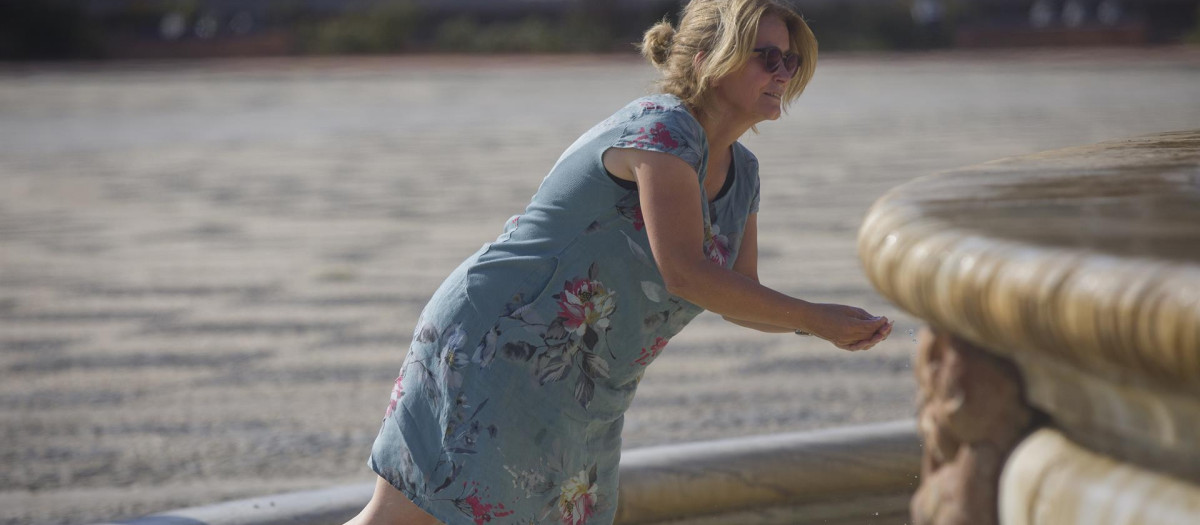 Una mujer se refresca en Sevilla