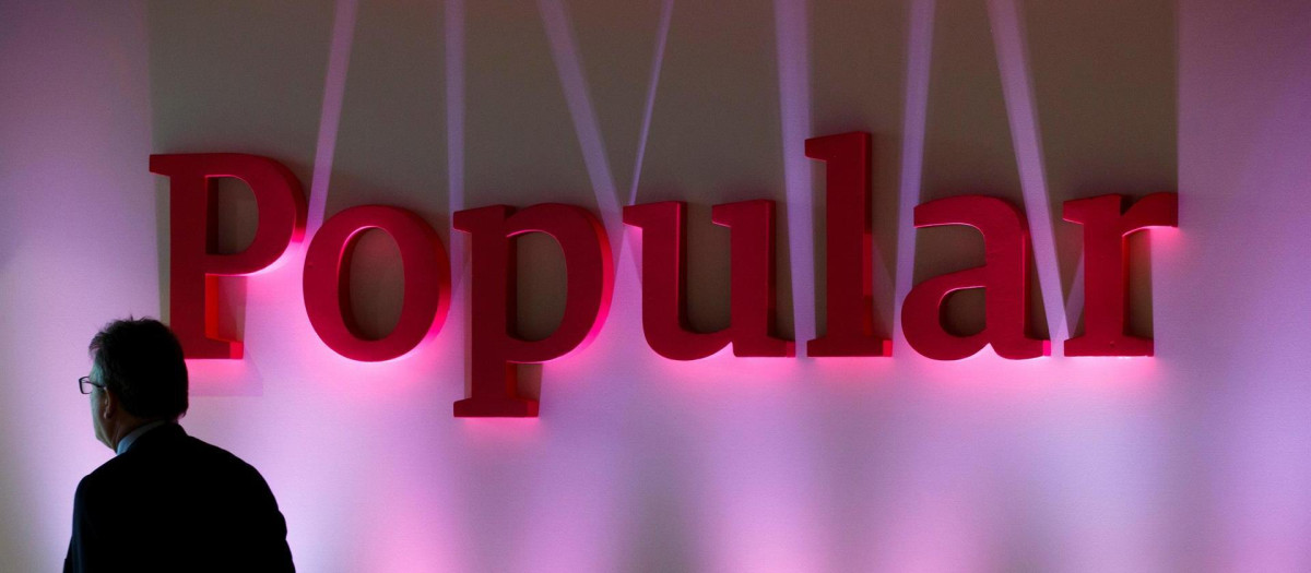 Un hombre camina por delante del logo de Banco Popular durante una presentación de resultados