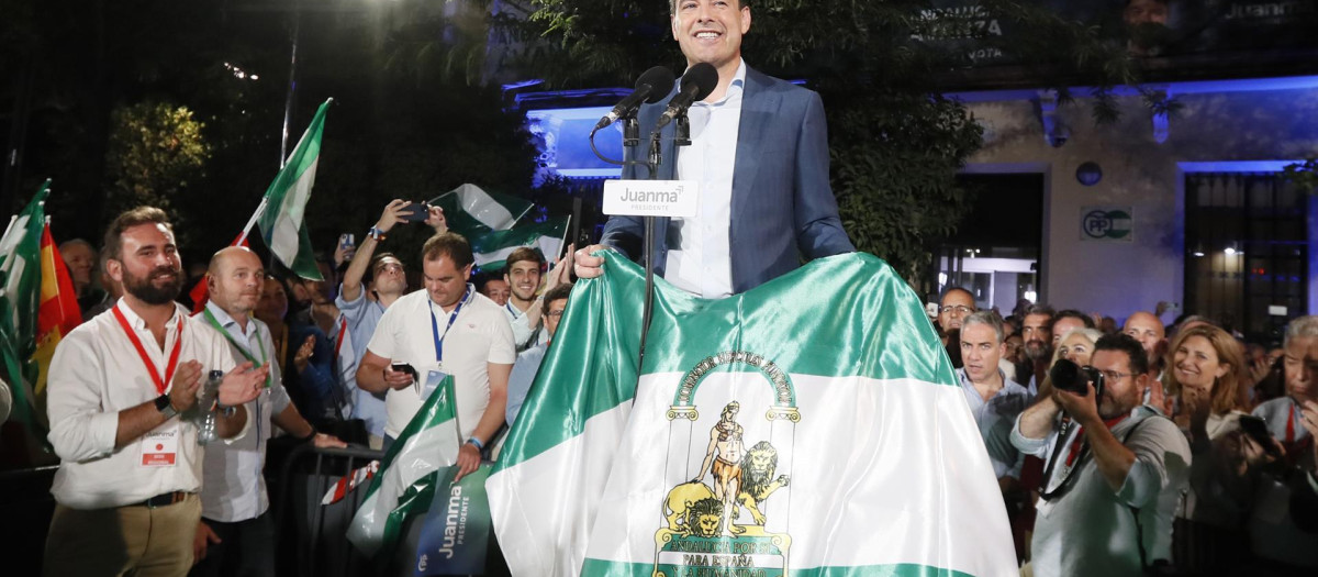 El presidente de la Junta de Andalucía, Juanma Moreno, posa con la bandera de la comunidad en la celebración de su victoria electoral