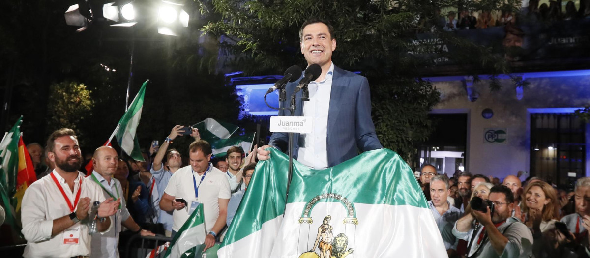El presidente de la Junta de Andalucía, Juanma Moreno, posa con la bandera de la comunidad en la celebración de su victoria electoral