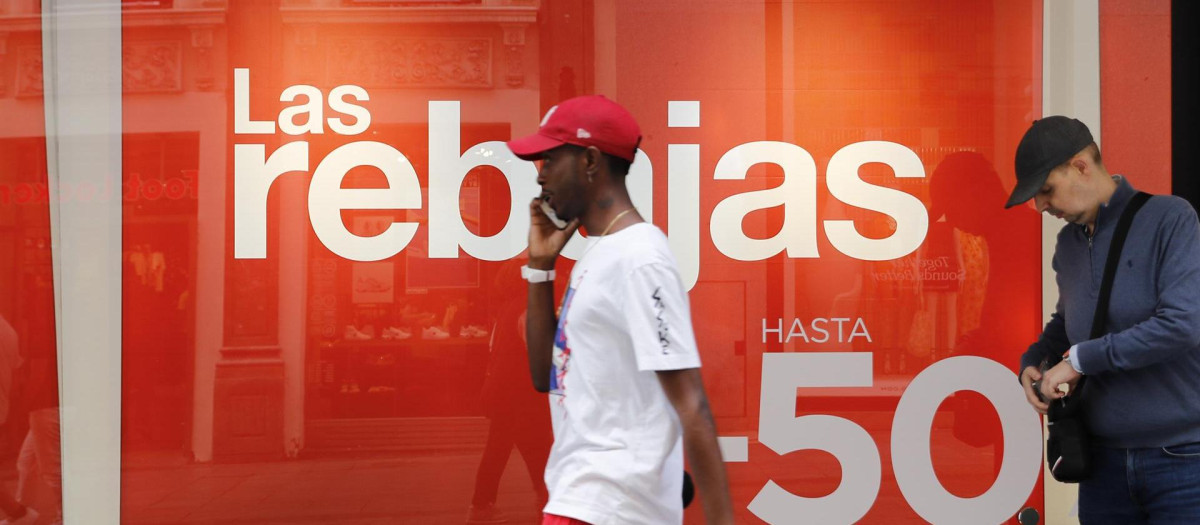 Un hombre pasa junto a un comercio de Madrid, que anuncia este jueves el comienzo de las rebajas de verano