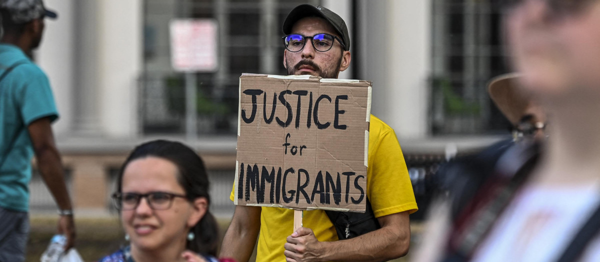 Un hombre sostiene una pancarta durante una vigilia por los 53 migrantes que murieron en un camión en Texas