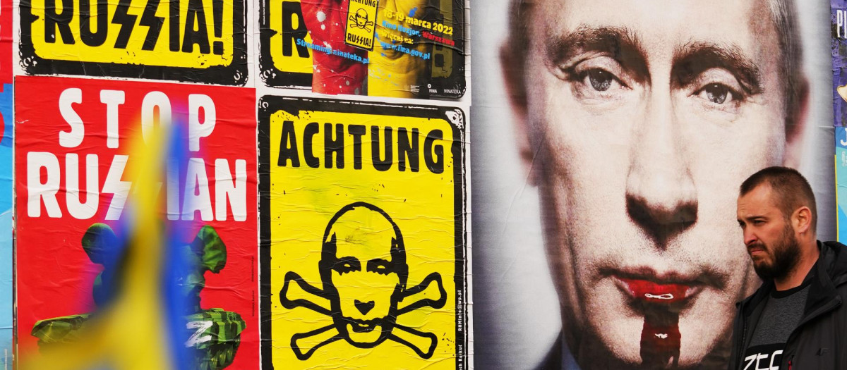 Un hombre pasa junto a una pared con carteles que representan al presidente ruso, Vladimir Putin, en Varsovia, Polonia