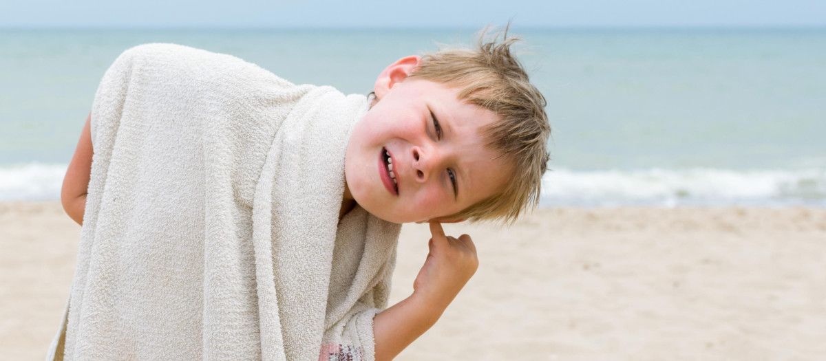 Un niño en la playa con problemas en el oído
